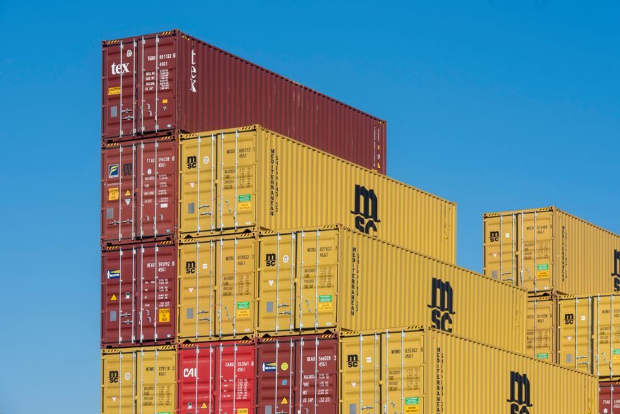 Shipping containers stacked several high against a blue sky