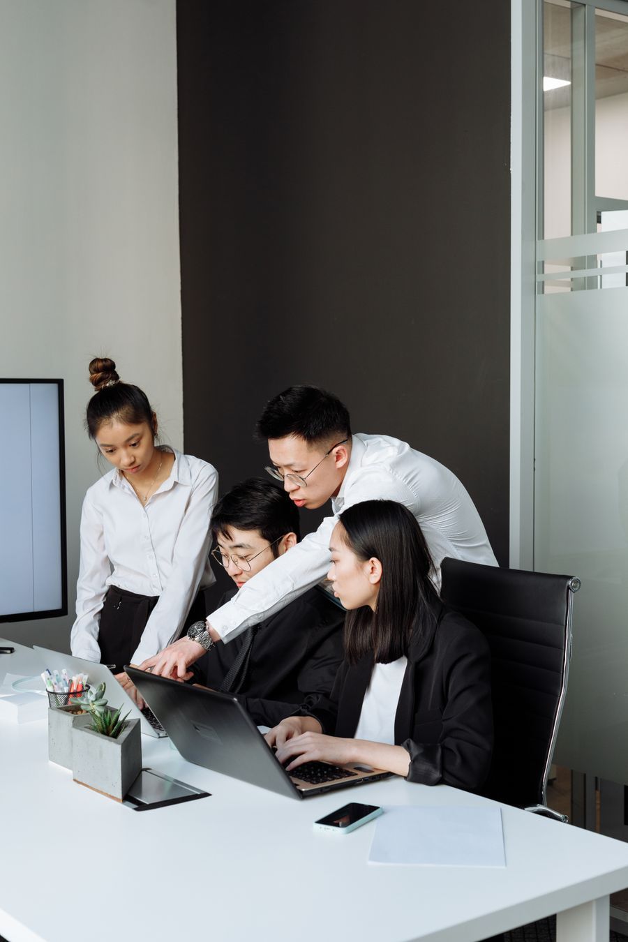 A team of four gathered around a laptop in an office