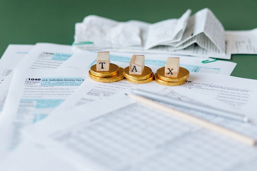 Stacks of coins on tax paperwork, with a receipt roll behind