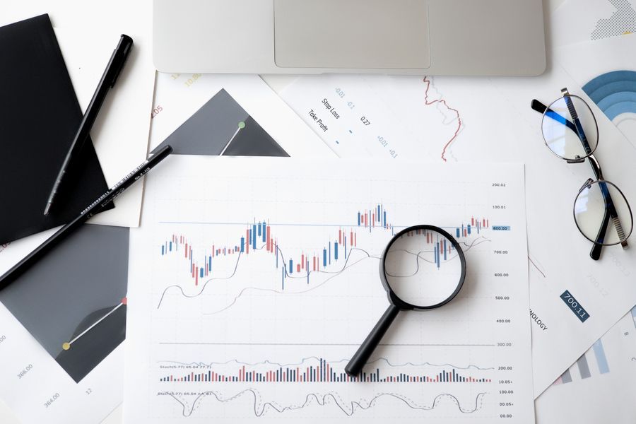 Printed cost charts on a desk with a magnifying glass and glasses