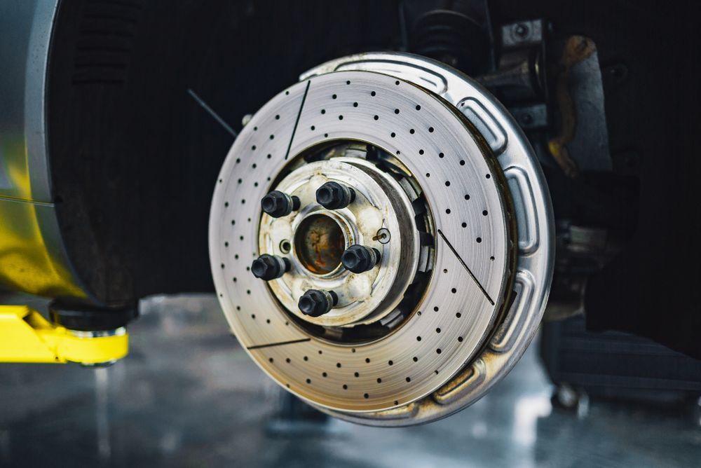 A drilled brake disc on a car hub in a workshop