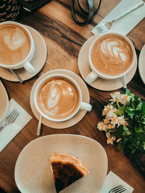 Freshly made coffees and cake on a cafe table