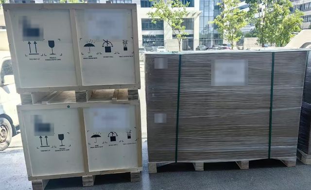 Shipping crates on wooden pallets, with a wrapped and strapped pallet beside them
