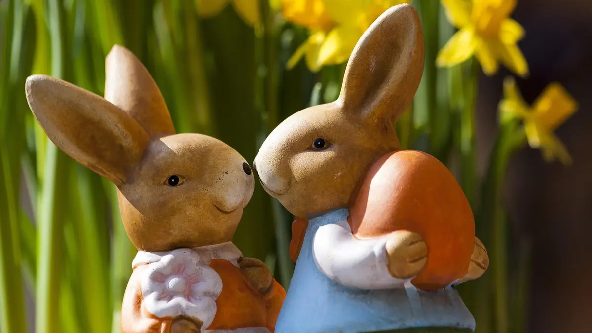 A pair of Easter bunny figurines with an Easter egg.