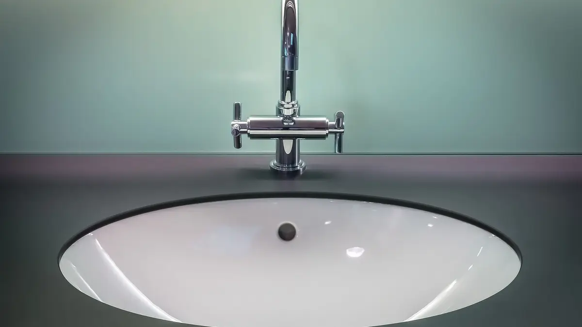 A chrome tap and sink in a bathroom.