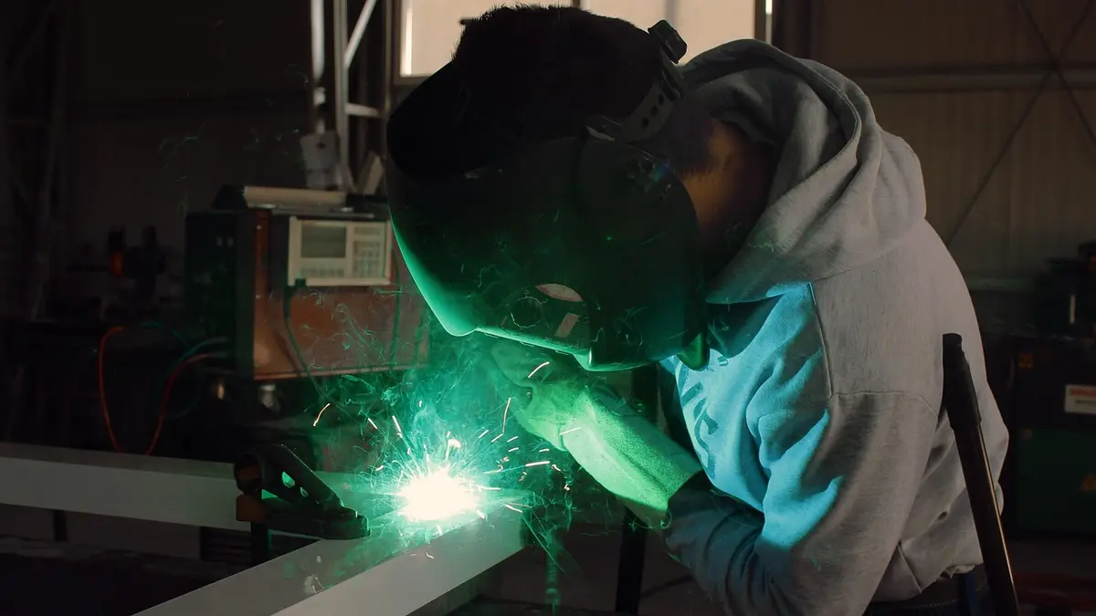A worker welds metal in a factory.