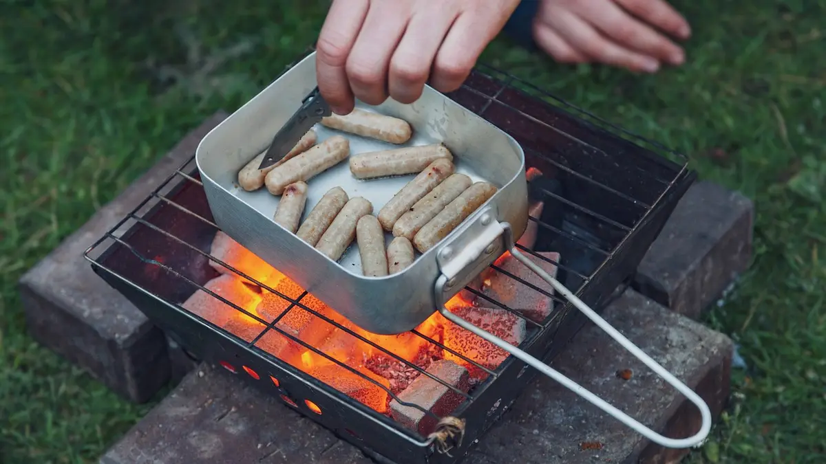 A mess tin with sausages at a barbecue.