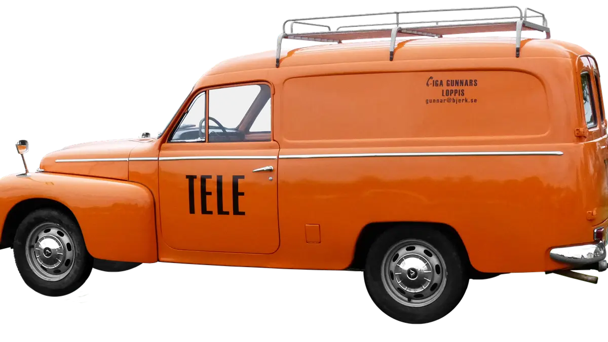 An orange classic Volvo van without side windows at a car show.