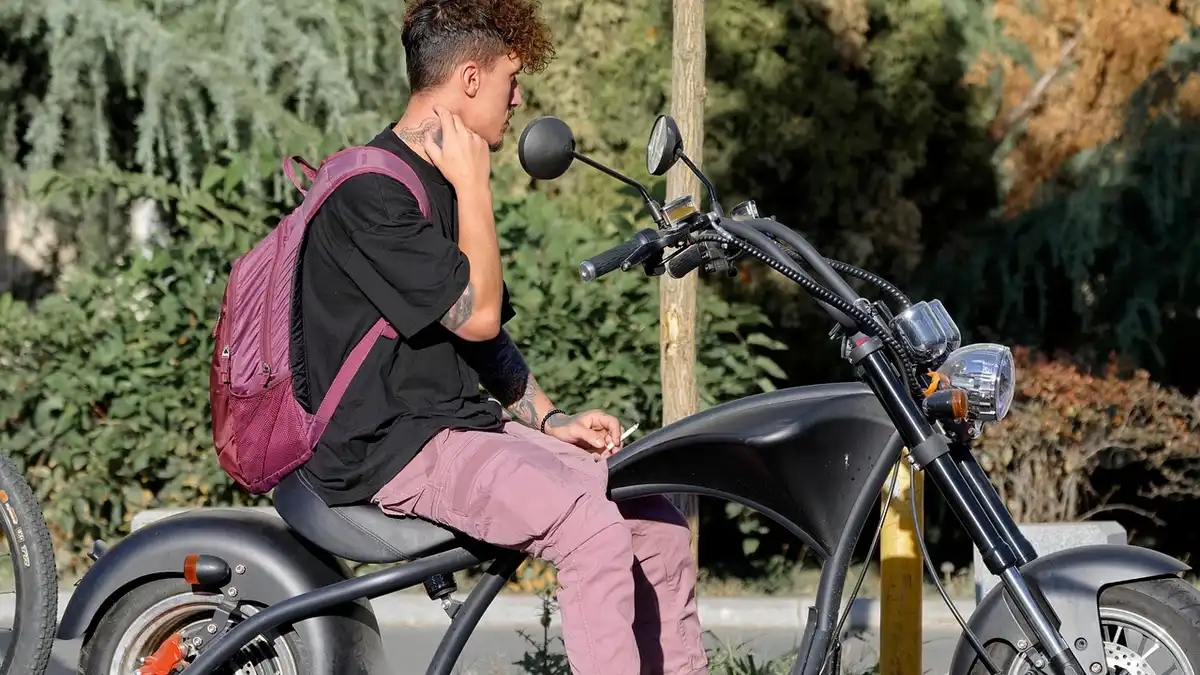 A man with an electric motorcycle on a street.