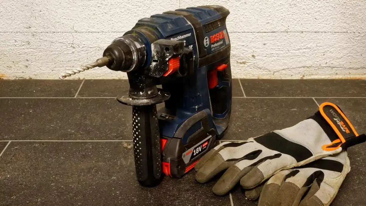 An SDS power drill and protective gloves at a construction site.