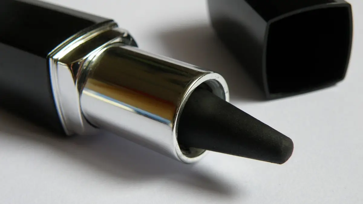 A black eyeliner pencil with cosmetics.