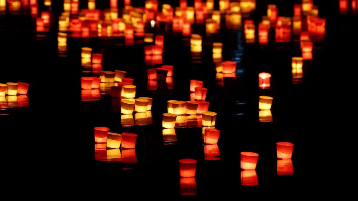 Floating candles glow on the water at night.