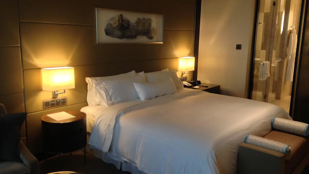A bed with a duvet in a hotel room.
