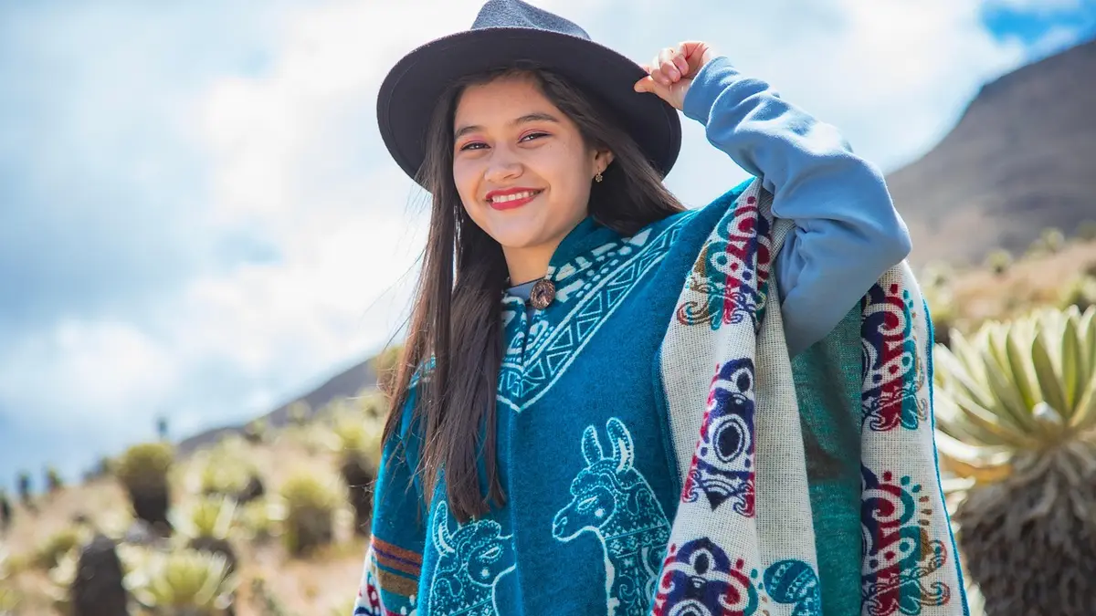 A woman wears a poncho and hat outdoors.