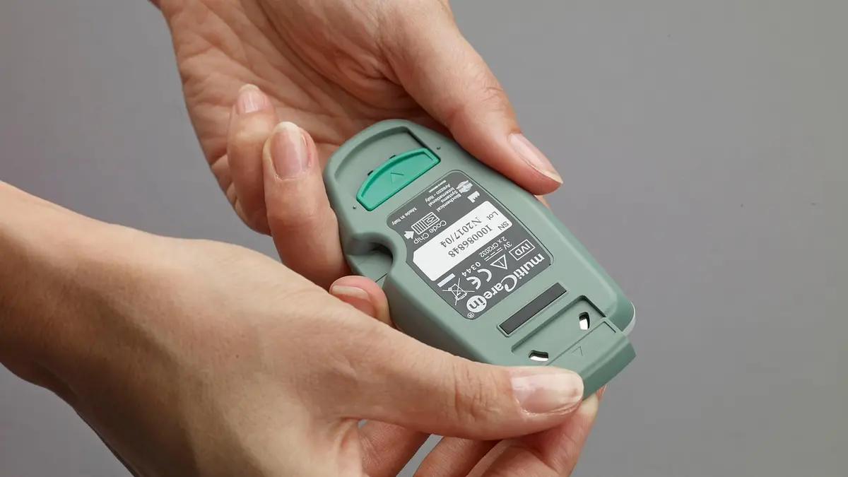 Hands holding a glucometer.