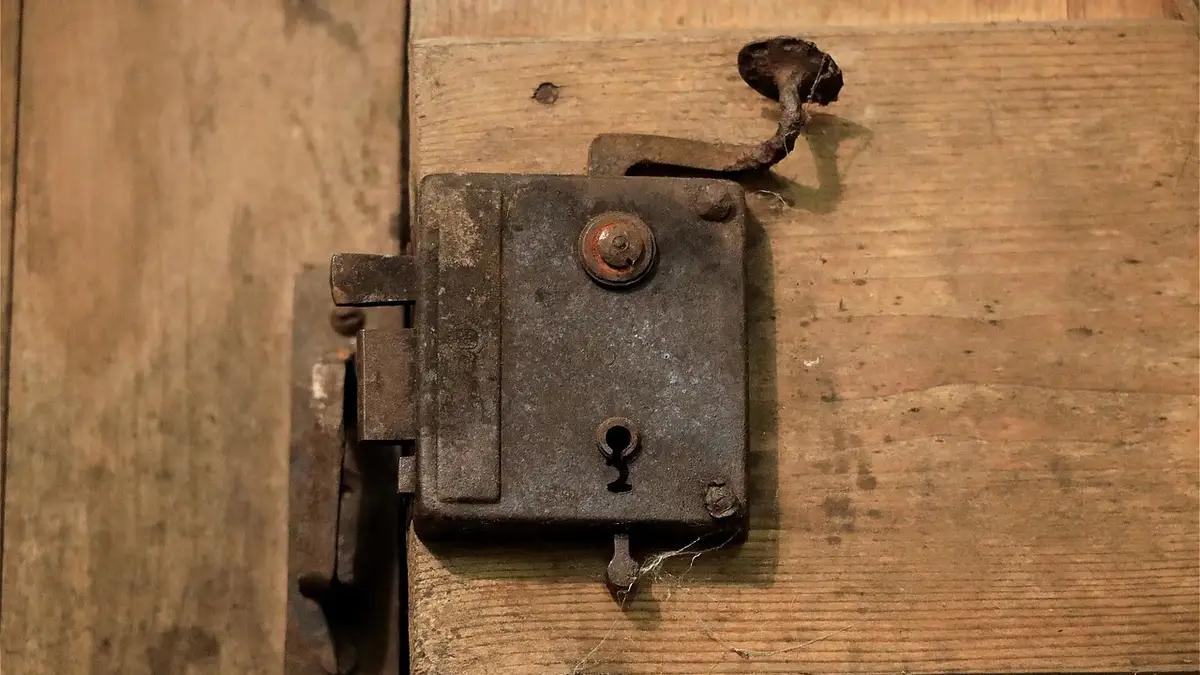 A metal door lock, handle and keyhole on a wooden door.