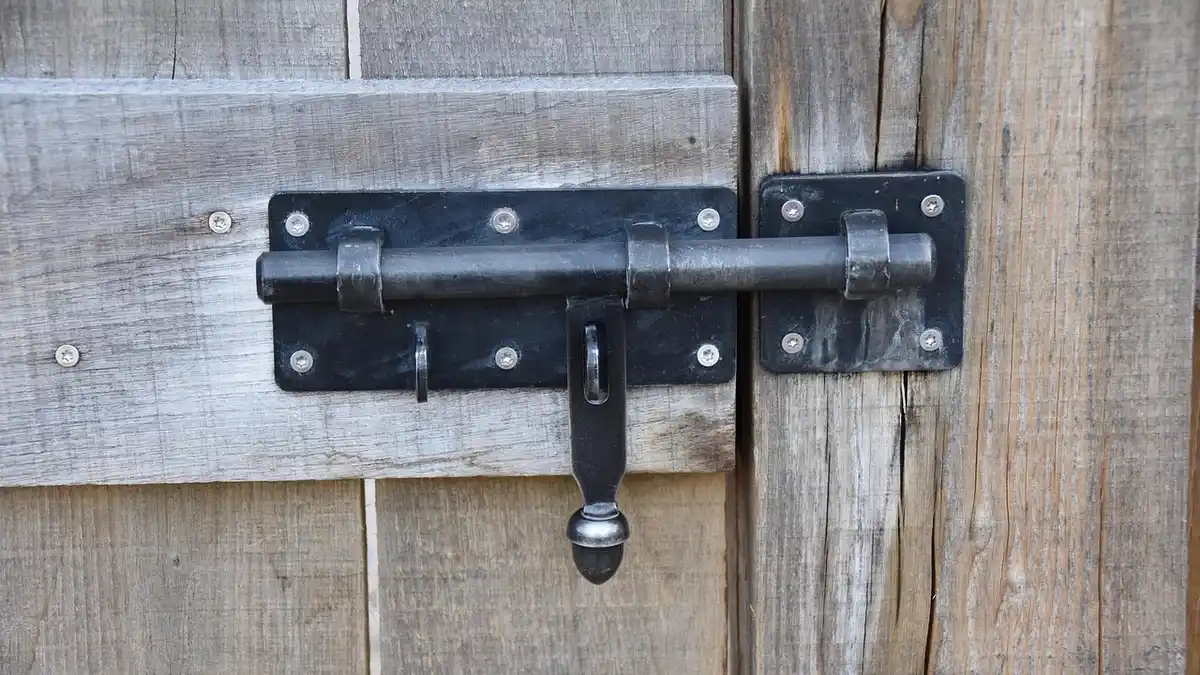A black door lock on a wooden door.