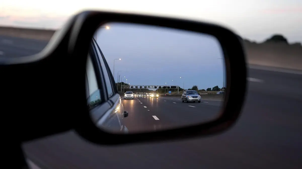 A car rear-view mirror on a road.