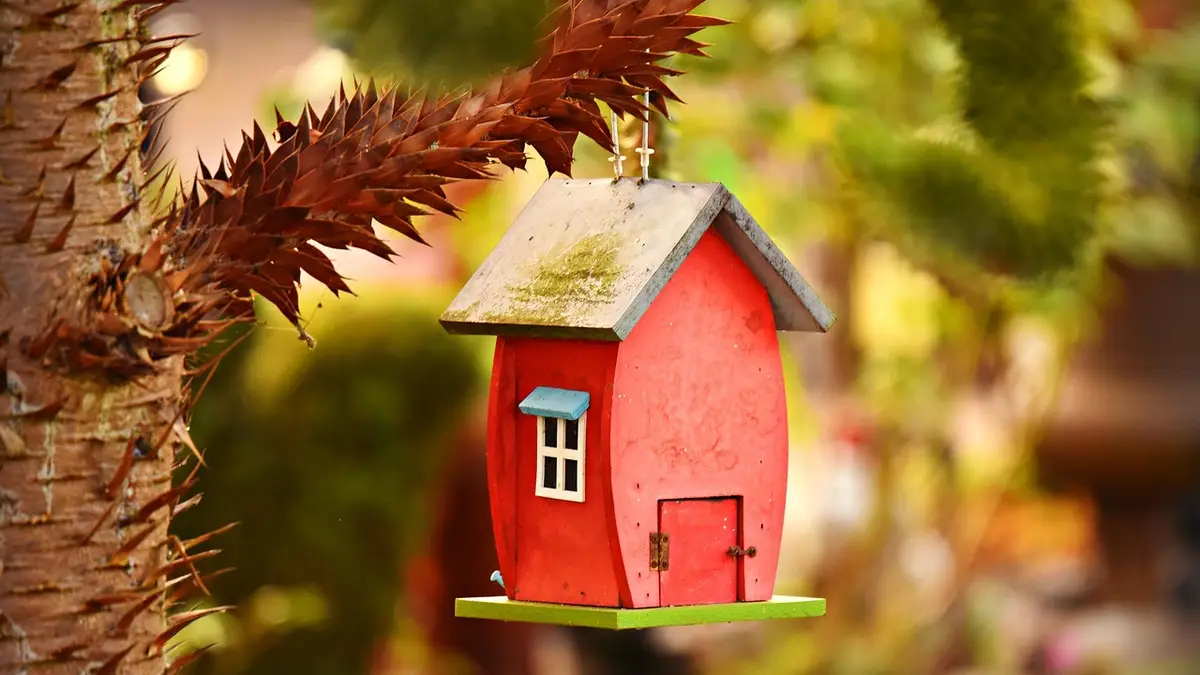 A handmade wooden bird nesting box in a garden.