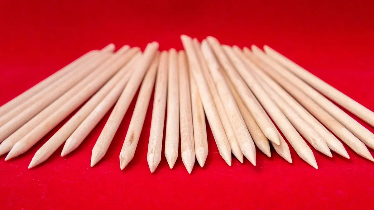 Wooden manicure sticks against a red background.