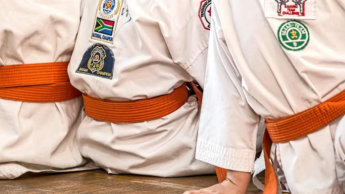 Seated athletes wearing karate uniforms and belts.